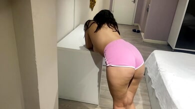 Curvy brunette bends over a white table in slow motion to present her ass for slapping