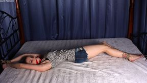 Cleavegagged barefoot Lisa, dressed in leopard tank top and short jeans shorts, bound on the bed with her hands tied to the headboard and her feet tied to the footboard, struggles and wiggles (HD MOV)