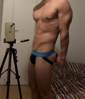 Young fit guy flexing in a jockstrap