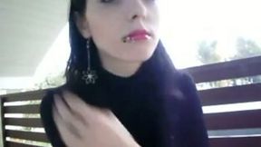 Beautiful brunette enjoys smoking a cigarette in front of a webcam