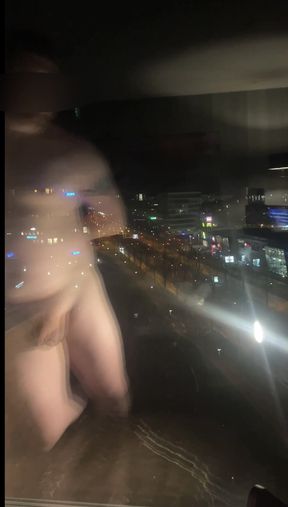 standing naked in front of the hotel window along a busy road