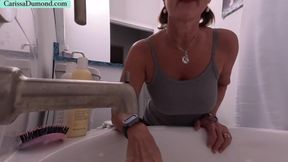 Carissa washes and conditions her hair while topless and kneeling at the tub