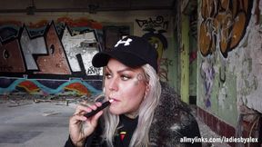 Blonde lady smokes an electronic cigarette on stair