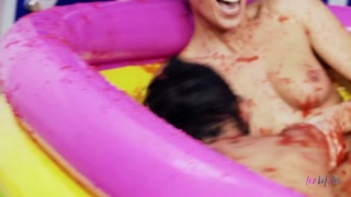 Brunette lesbians jump in a pool with food to wrestle and their big tits