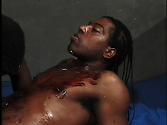 Lying on the wrestling mat, the black stud has his horny friend sucking his cock