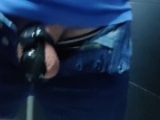 Locked in a chastity cage, man is pissing in a public toilet