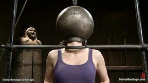 ”Bound redhead with head in metal ball”