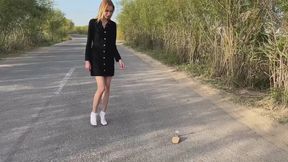 a girl walks through a muddy area in sandals and white socks, at some point she realizes that she is uncomfortable in sandals and she takes them off and walks in just socks through the mud