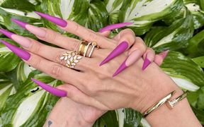 New Purple Color Long Nails, Sharp Stilettos, Palms, Long Fingers in the Garden with Flowers