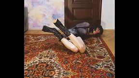 Crossdresser in armbinder, with gag and butt plug lies on the floor tied up