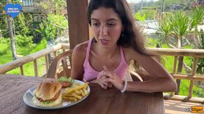 Sweet girl licks messy burger with cum on her face in a busy caf&#x00E9;