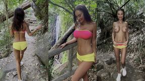monika fox in pink top and yellow shorts walks through jungle and waterfalls
