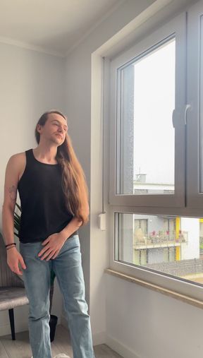Long-haired boy masturbates in front of big window
