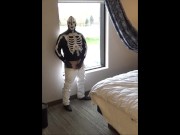 skeleton mask in pantyhose and jeans at hotel window