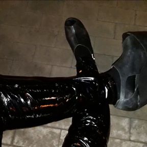 a crossdresser in high wedge platform shoes and latex leggings is walking the streets at night