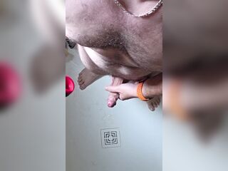 Throbbing dick glistens beneath running water