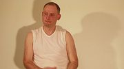 Semi erect and naked Jonathan puts on a white t-shirt masturbates his uncut shaved cock to hard erection