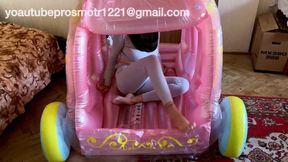 Nastya, barefoot and in gray leggings, tramples on an inflatable carriage, steps on it, pushes it, walks on it, stands on it, and lets out air. foot fetish, crush fetish, inflatable