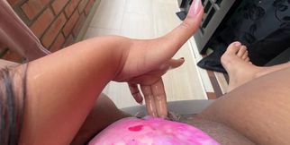Teen sits on the balcony and plays with her wet pussy