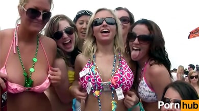Blonde lesbians kiss and embrace at a crowded beach party in matching bikinis