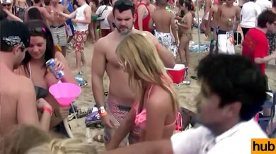 Blonde lesbians kiss and embrace at a crowded beach party in matching bikinis