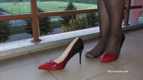 Dipping classic red high heels on balcony