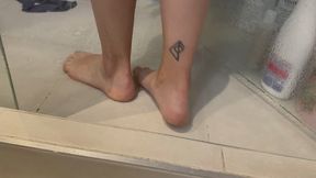 Mujer se masturba mientras se toca y se masaje los pies con jabón y agua en la ducha