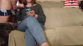 The milf looks at the phone while giving him a handjob