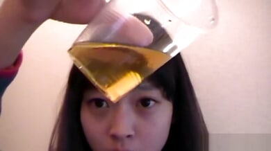 Young Asian performer sips golden fluid in intimate bathroom session