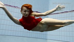 Redhead beauty Ala swims under the water in the pool