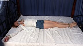 Tapegagged barefoot Mary, wearing tank top, shirt and jeans shorts, bound on the bed with her wrists tied to the bed posts and her feet tied to the footboard, is wiggling on the bed, trying to get loose (HD WMV)