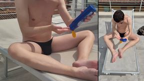 Guy in a thong puts on sunscreen