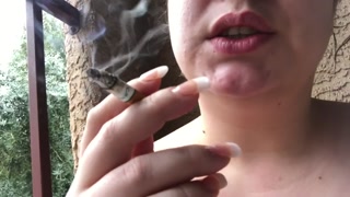 Smoking on balcony in a strappy top