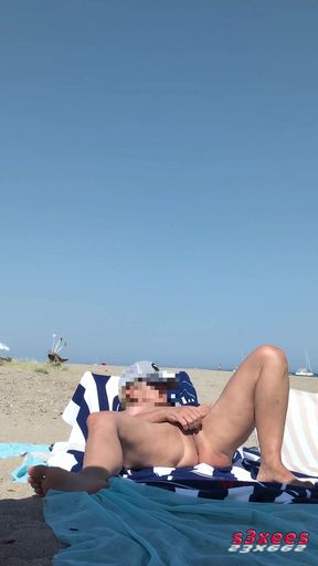 She masturbates her on the naturist beach in public with a voyeur who es by