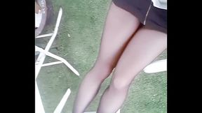 Young asian girl in sexy outfit and black pantyhose walks through apartment garden