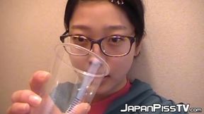 Sweet Japanese girl urinates in a cup while sitting on the toilet