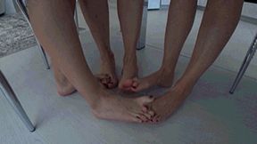 3 girls barefoot sitting at a table interlocking their toes d