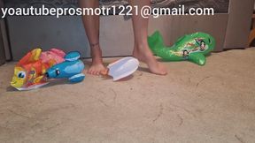 Nastya tramples inflatable toys with her bare feet, crushes them with her weight, destroys them