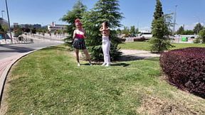 Two girls exposing their breasts to passersby on a dirty street corner.