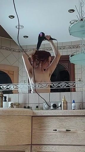 A Charming Woman Is Preening in the Bathroom in Front of a Mirror
