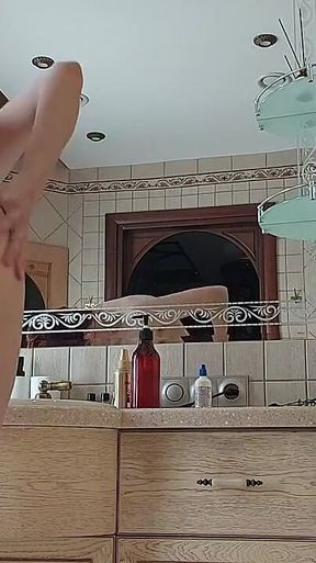 A Charming Woman Is Preening in the Bathroom in Front of a Mirror