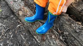 Sitting in rubberboots on woodpile