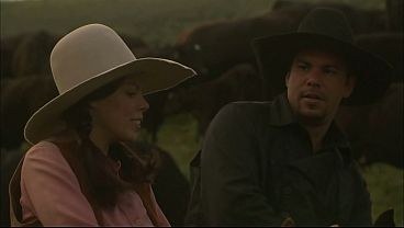 After laying down a blanket, she gets naked but keeps her riding chaps on as she fucks the...