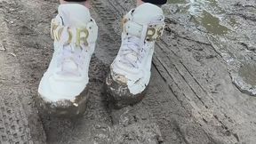 A girl in fashionable snow-white sneakers He walks on slippery, sticky mud and gets his hands dirty and crush her sneakers
