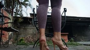A woman sitting with big legs crossed and high heels dangling from her feet (2)