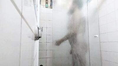 handsome guy brushing his teeth in the shower.