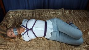 Tapegagged barefoot blonde Nancy in white shirt and light blue jeans, hogtied with violet hemp rope with her elbows tightly bound together, struggles on the bed (HD MP4)