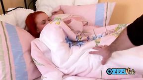 Teasing redhead spreads her long legs and fingers herself in bed