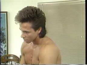 The hung stud sits on the edge of the bed while getting his cock serviced