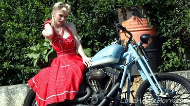 Blonde pornstar Casey Deluxe strips down in a red polka-dot dress beside a vintage motorcycle